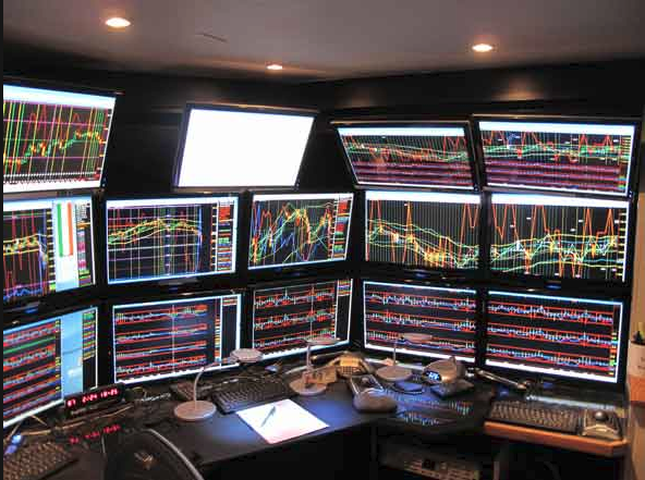 a traders desk with multiple screens